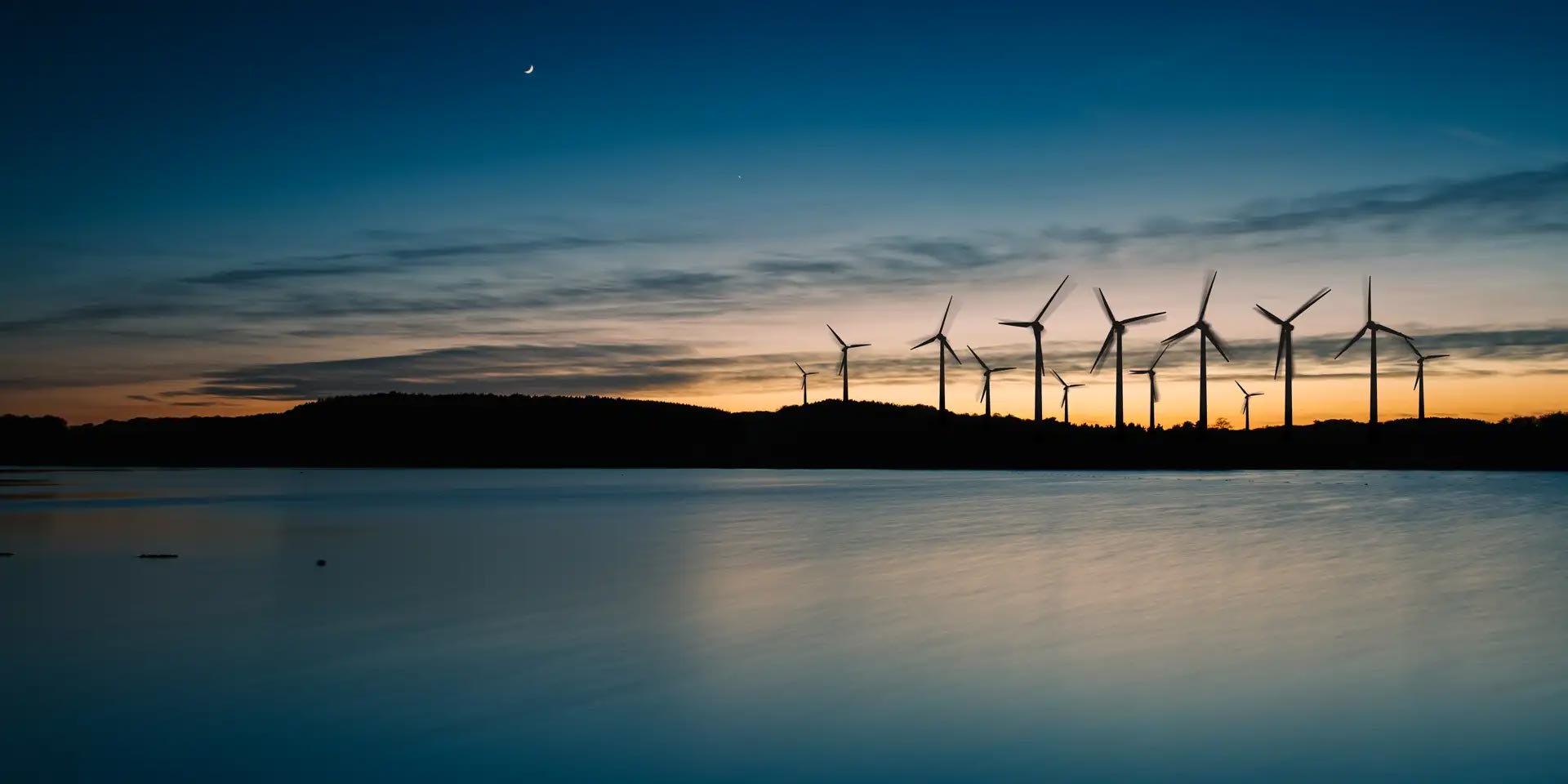 Wind farm with beautiful sunset by the water